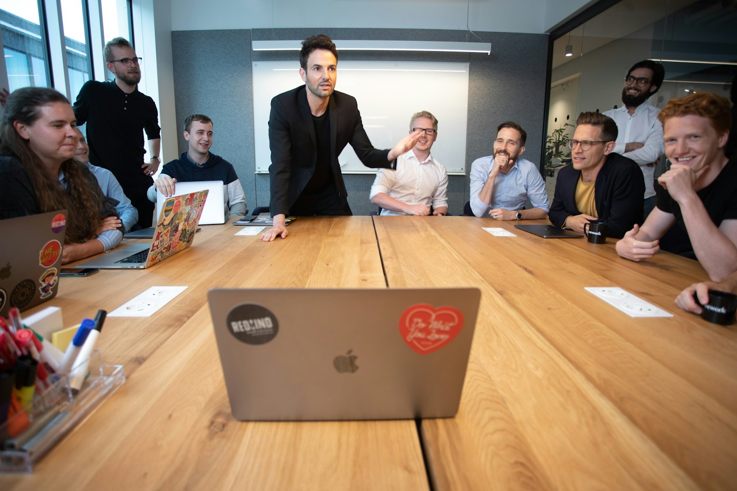Profesionales en una reunión alrededor de una mesa de conferencias de madera.