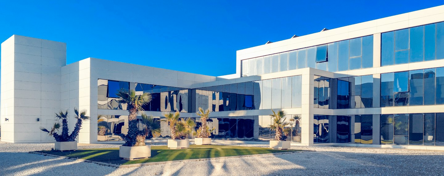 Edificio de oficinas moderno con palmeras en un día soleado.